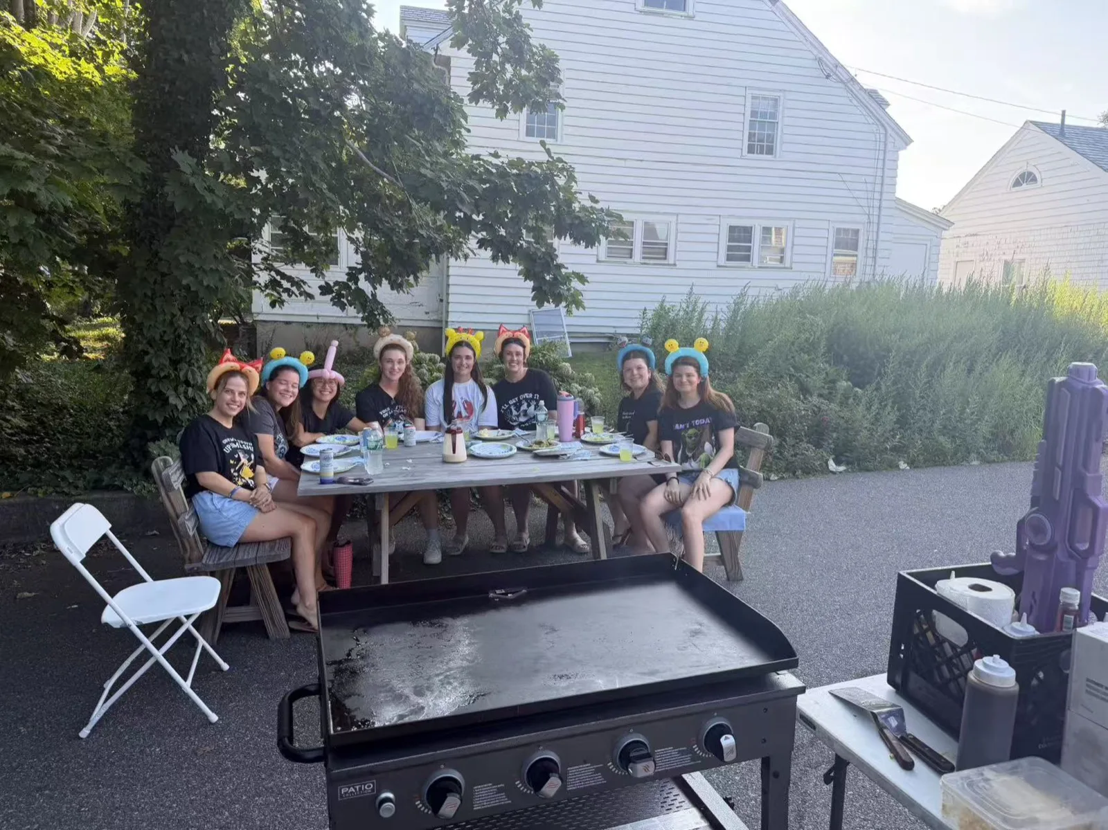 Guests seated at a picnic table for a daytime hibachi party in a Rhode Island backyard