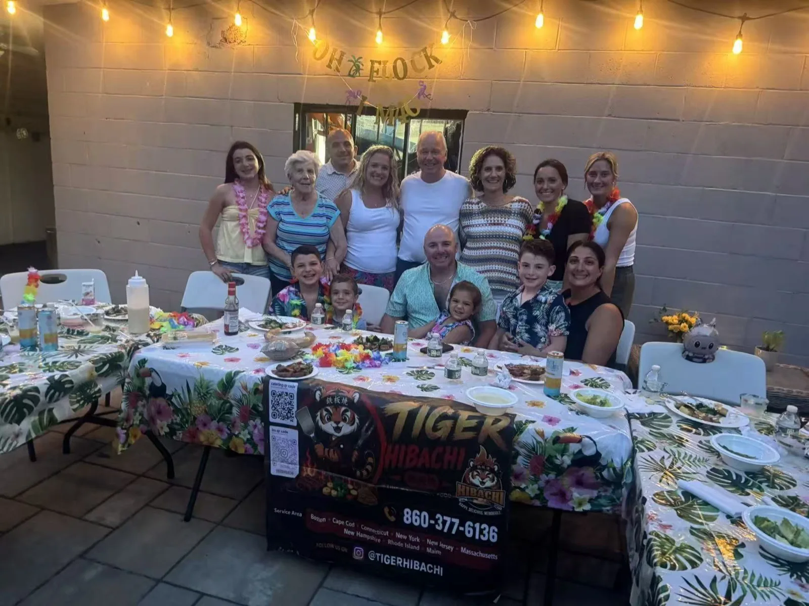 Extended family posing together around the dinner table at a hibachi party in a Rhode Island backyard