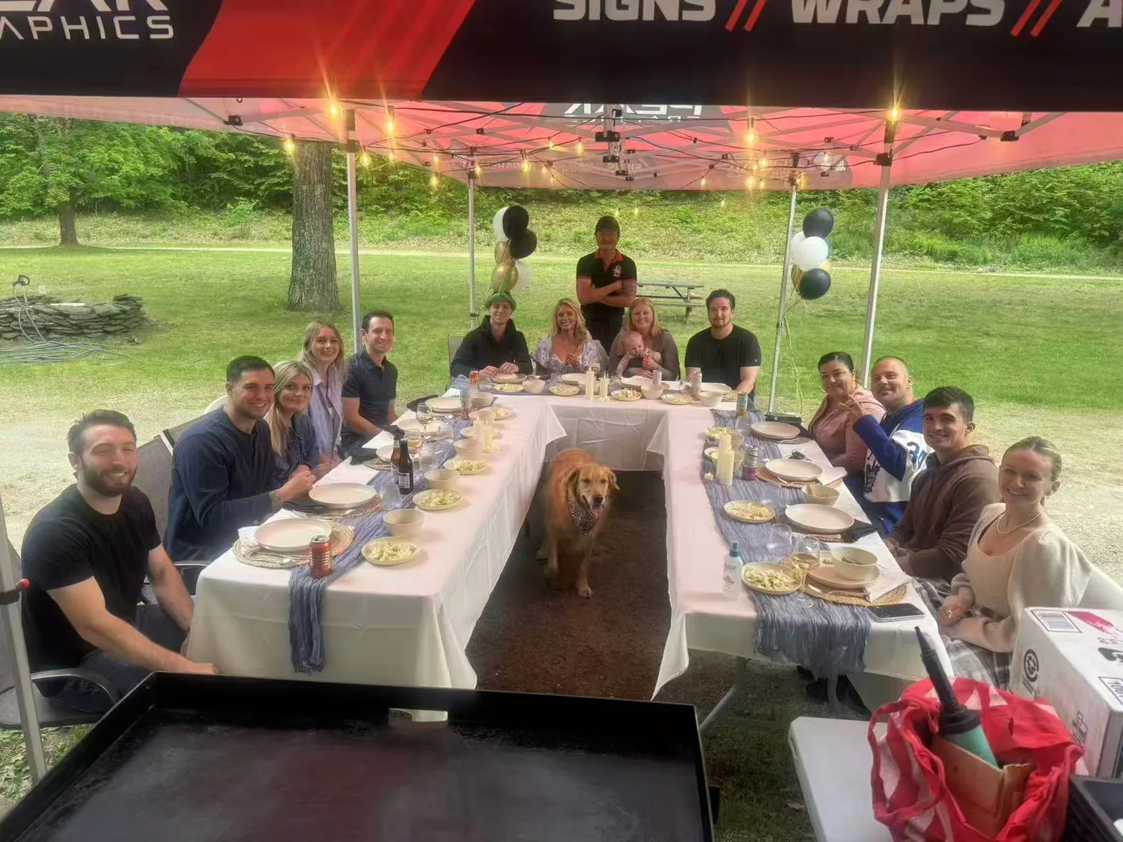 Long banquet table set for a hibachi catering party under a tent on a Rhode Island lawn