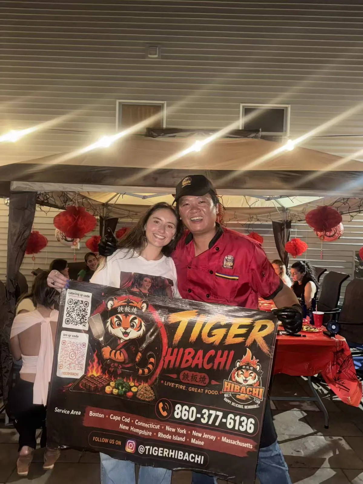 Tiger Hibachi chef posing with a guest holding the event sign at a Rhode Island party