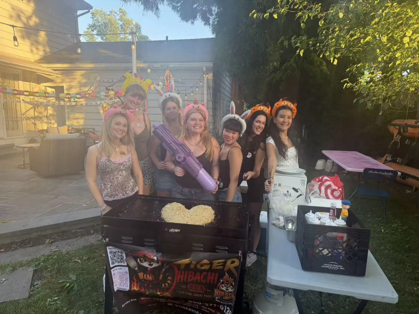 Group of women wearing animal-ear headbands posing beside the Tiger Hibachi cart in Rhode Island