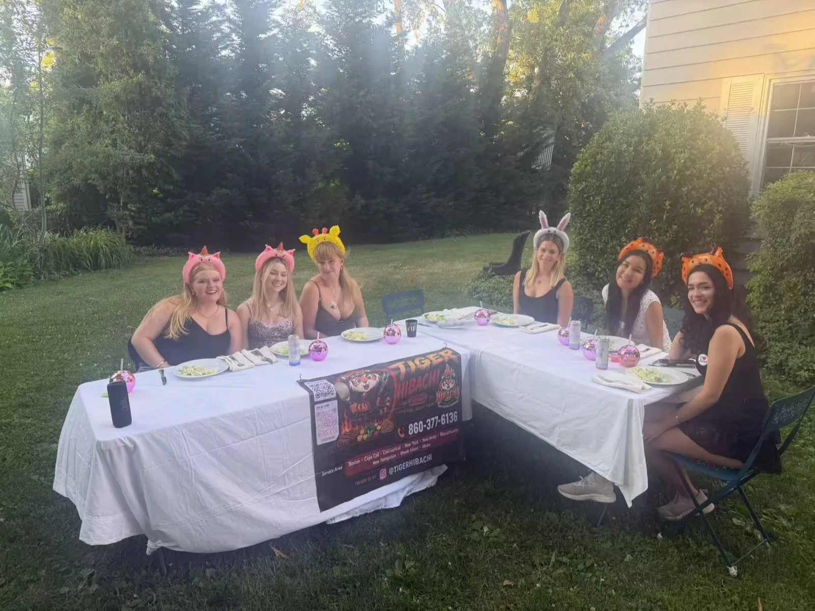 Guests wearing animal-ear headbands seated at a long dinner table for a hibachi party in Rhode Island
