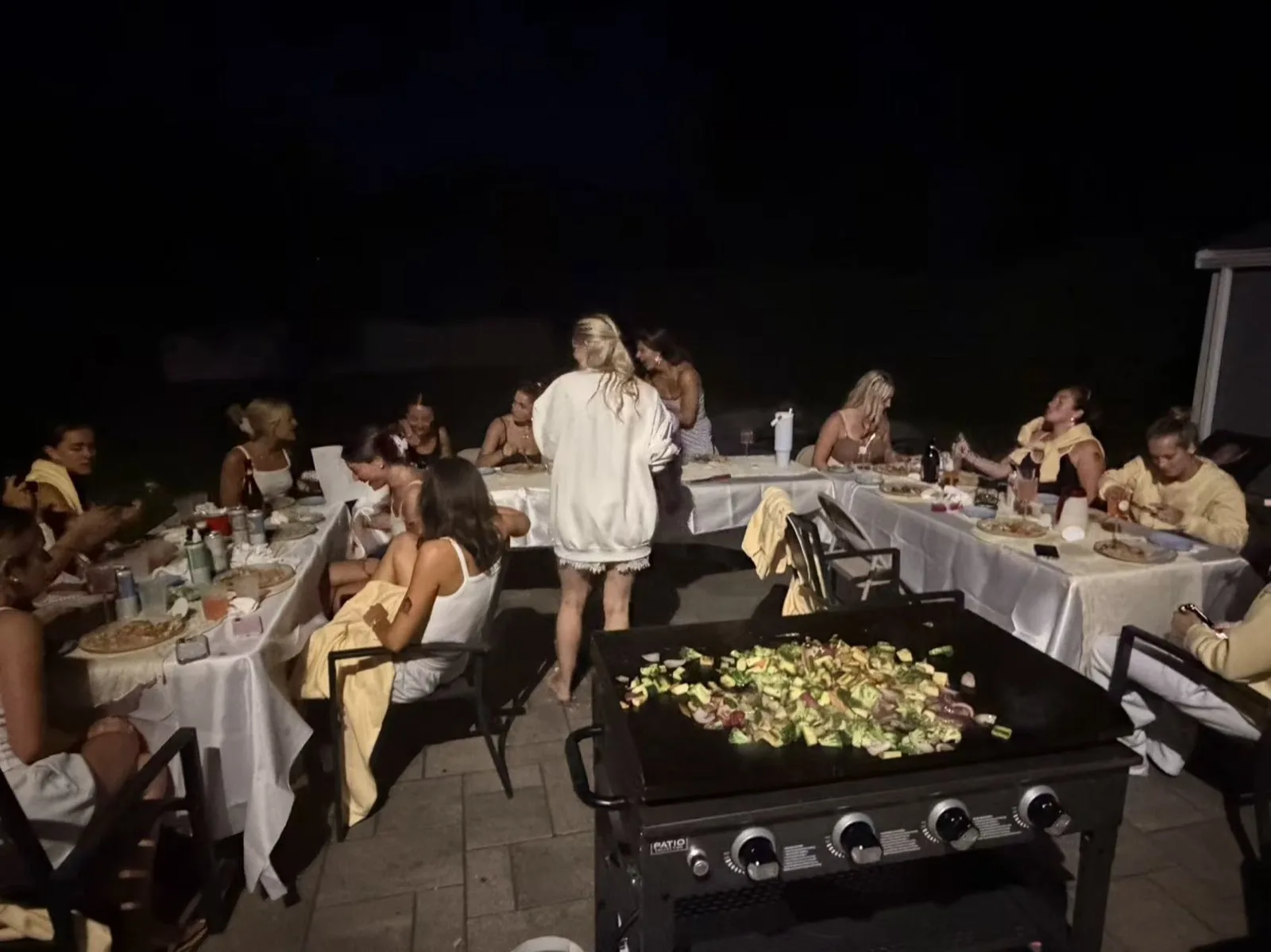 Guest dancing near the grill while the chef cooks at a nighttime hibachi party in Rhode Island