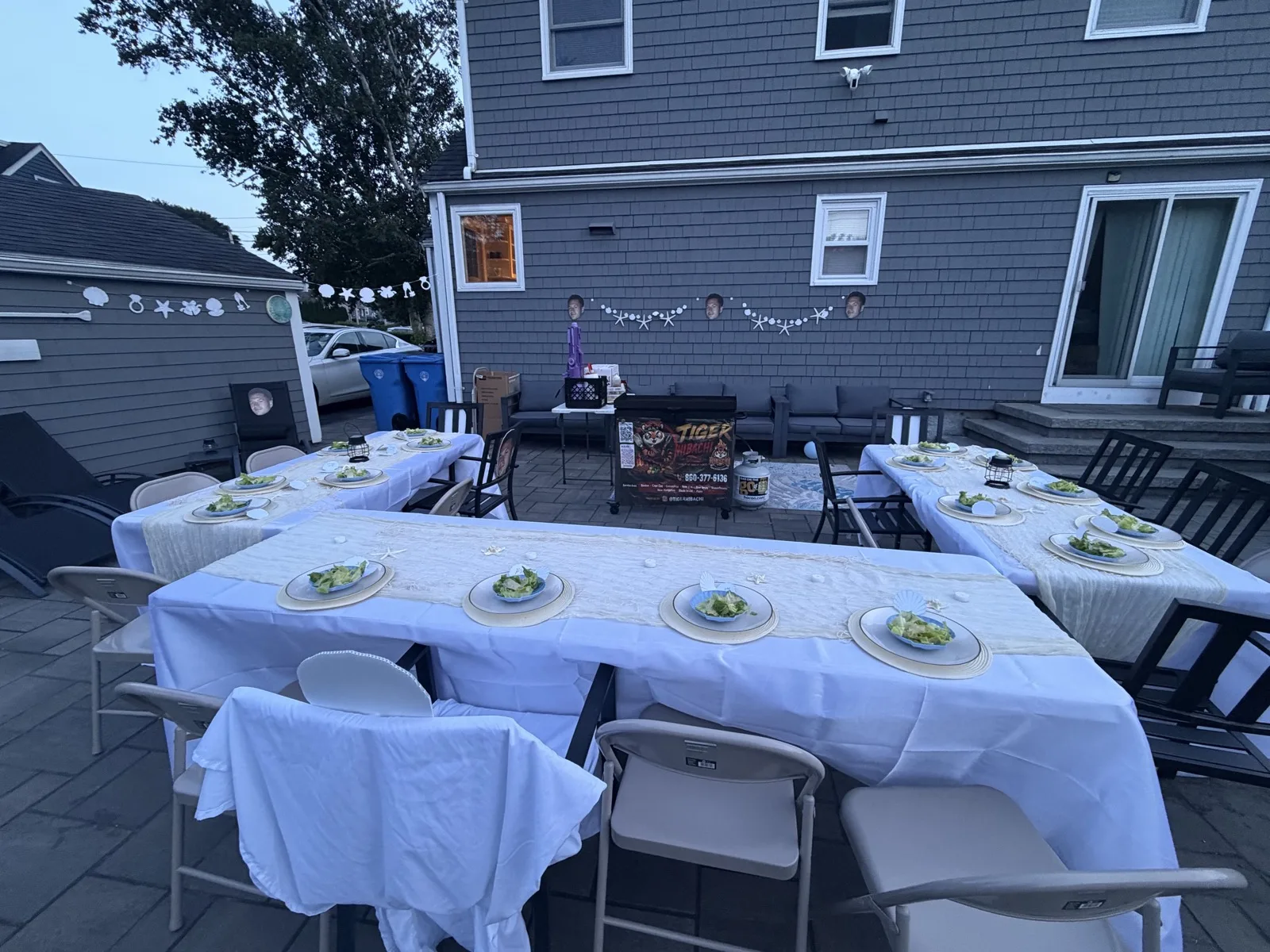 Empty dinner table set for a Tiger Hibachi party at sunset in a Rhode Island backyard before guests arrive