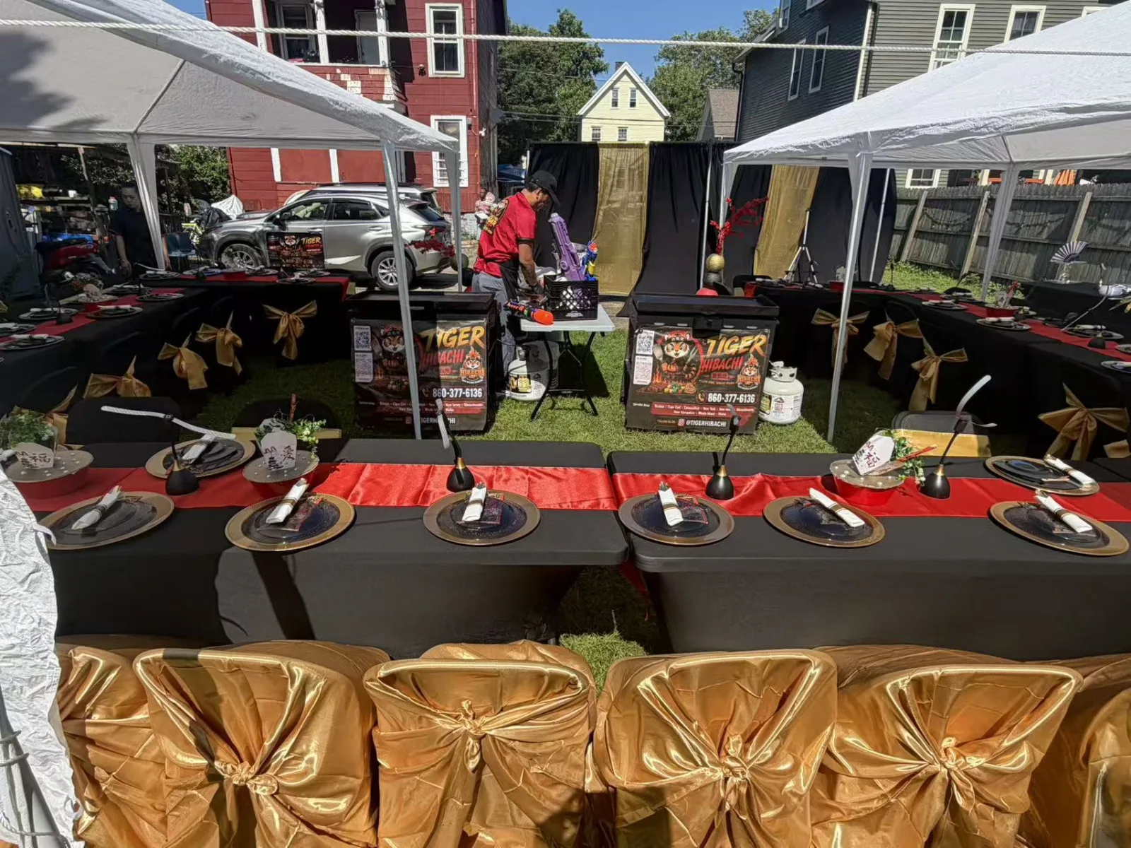 Long tented dinner tables set with gold chair covers and place settings for a Tiger Hibachi party in Rhode Island