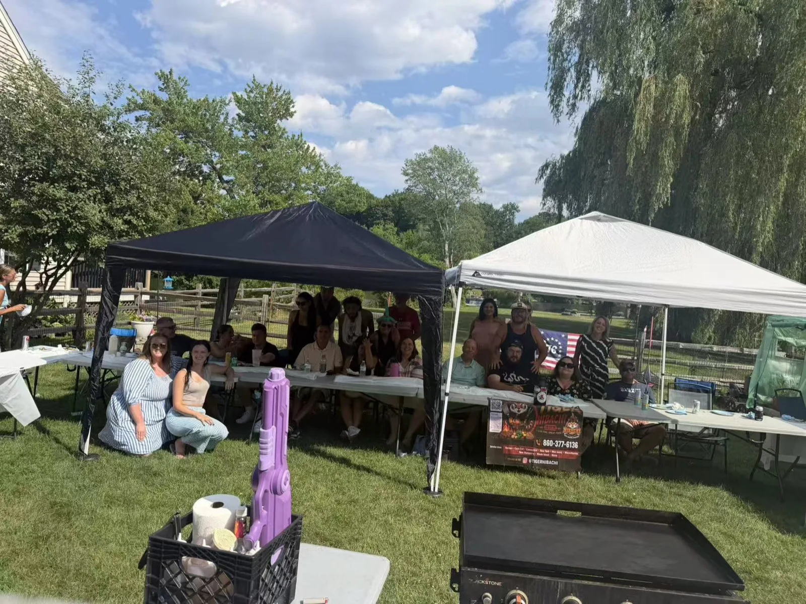 Guests seated at a picnic table under a party tent at a Tiger Hibachi booking in Rhode Island