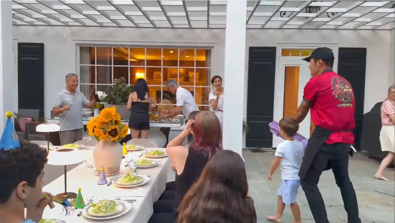 Hibachi chef setting up a mobile teppanyaki grill on a Rhode Island lawn before a party